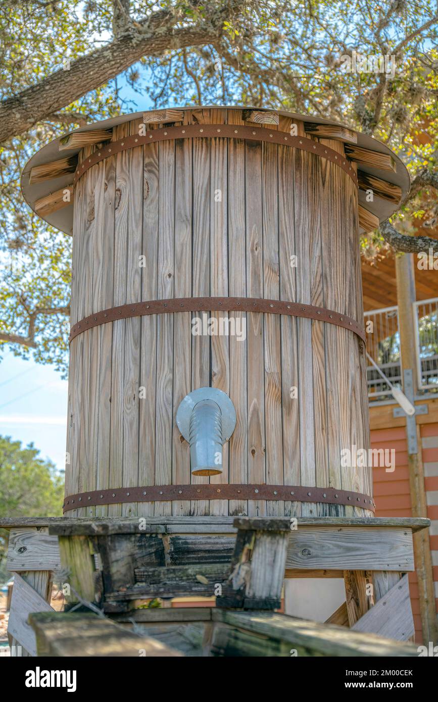 Primo piano di un serbatoio d'acqua in legno con tubi e canali d'acqua davanti al lago Austin, Austin, Texas. Serbatoio di acqua di legno contro gli alberi e la casa a t Foto Stock