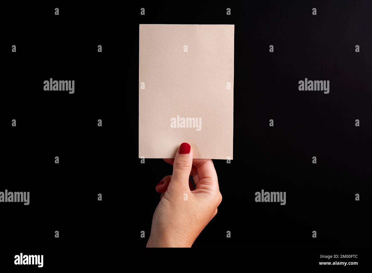cartolina in formato verticale, tenuta da una mano femminile su uno sfondo nero con spazio copia e mockup Foto Stock