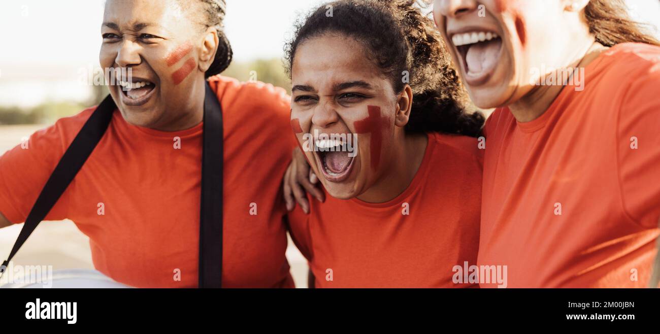 Tifosi femminili che esultano mentre guardano una partita di calcio allo stadio - concetto di intrattenimento sportivo Foto Stock