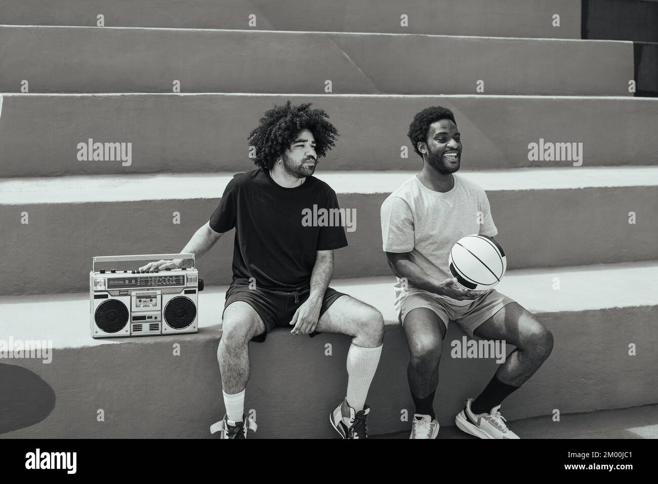 Felici afro-americani che ascoltano musica all'interno del campo da basket con stereo boombox vintage - Urban Street people lifestyle Foto Stock