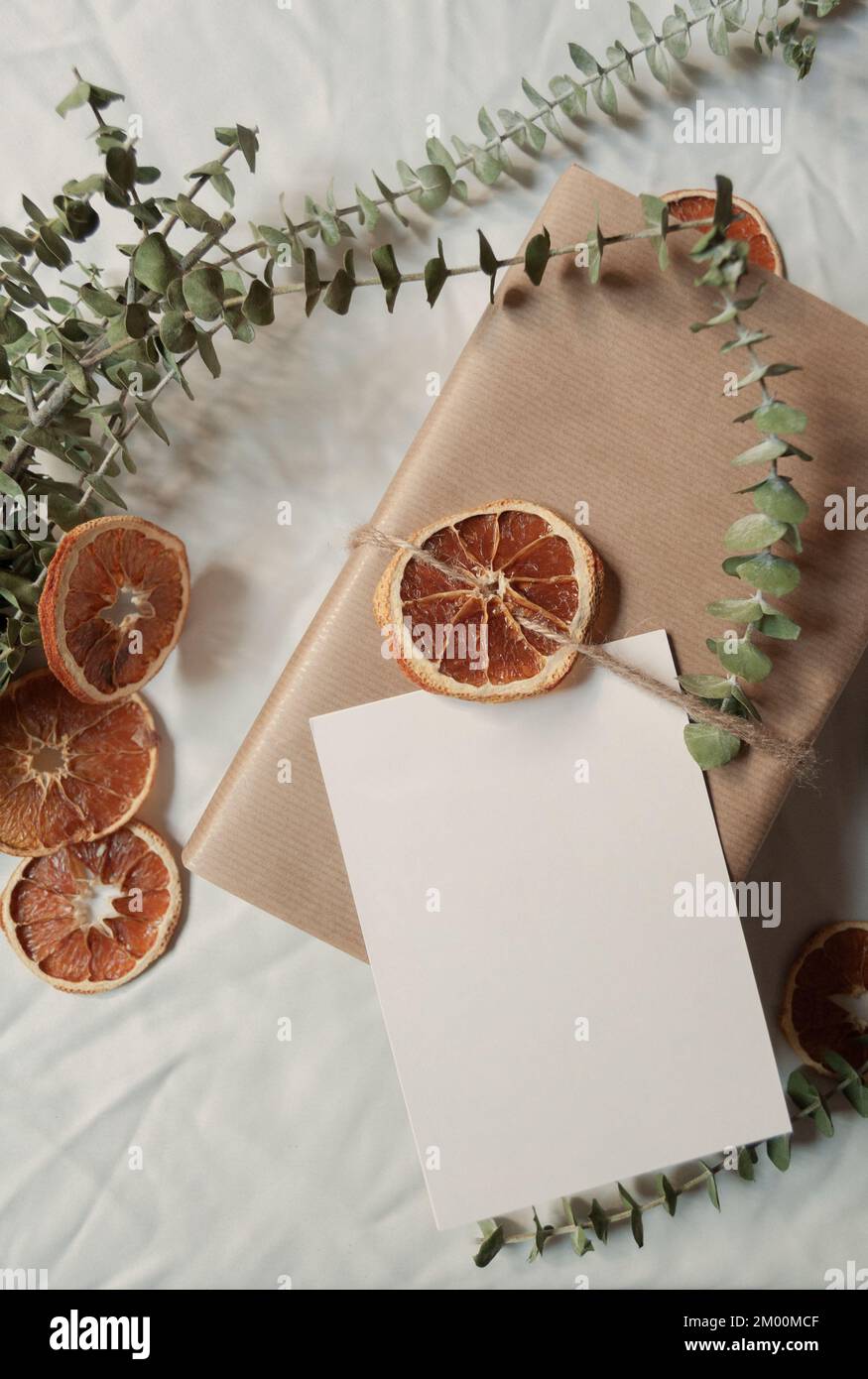 Piccola scatola di affari e cartolina di saluto ancora vita in bianco backgroung con le fette di arancia essiccate e le foglie di eucalipto eco-friendly imballaggio Foto Stock