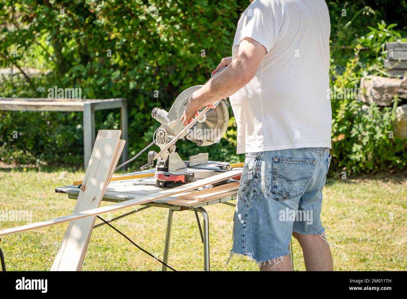 Immagine dell'uomo usando la sega circolare all'aperto che taglia il legno per il progetto di hobby domestico del diy Foto Stock