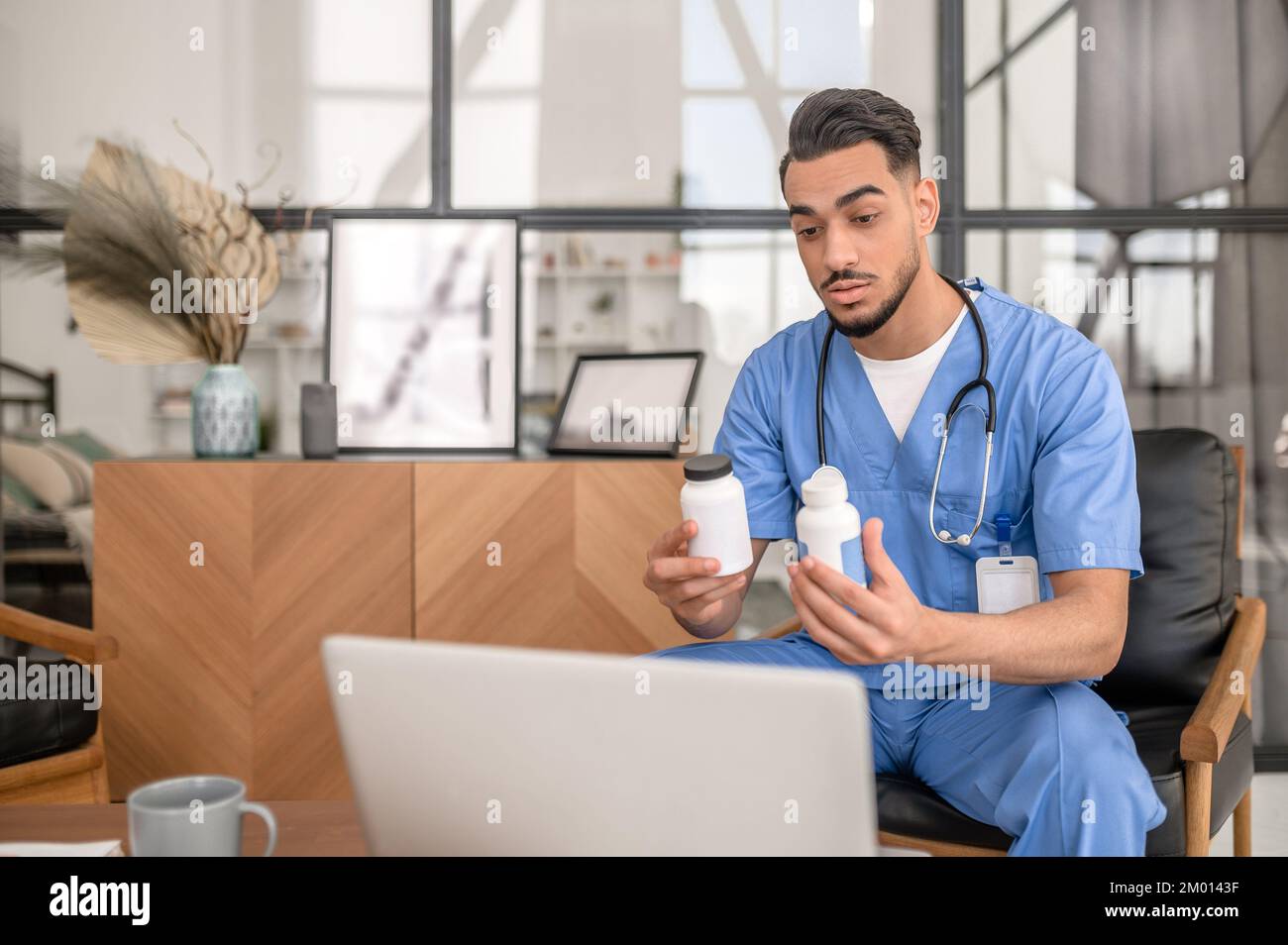 Medico seduto al computer portatile che prescrive farmaci a un paziente durante la visita medica virtuale. Foto Stock