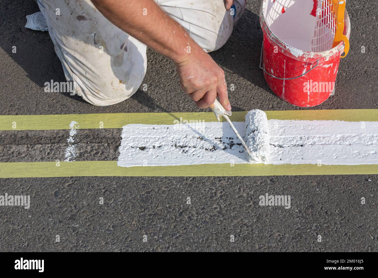 La segnaletica stradale viene applicata a mano con un rullo per vernice Foto Stock