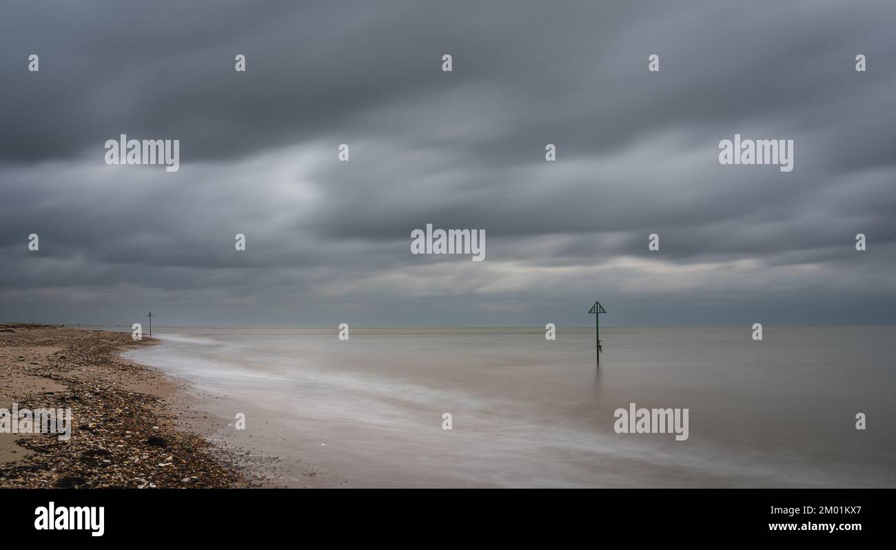 Spiaggia di Mersea Island in una nuvolosa giornata invernale. Esposizione lunga, foto moody. Foto Stock