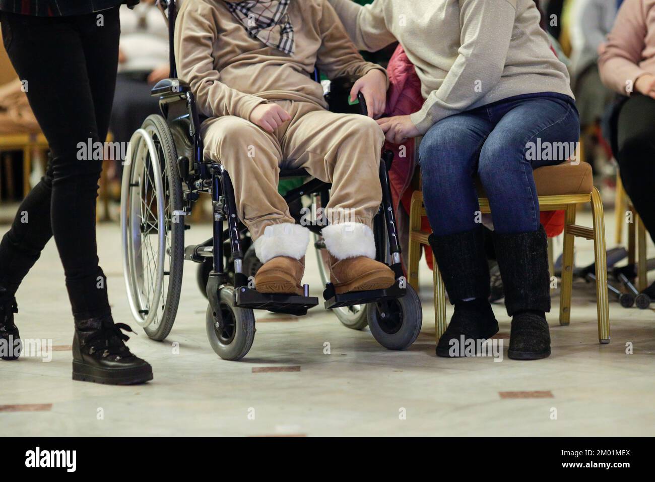 Profondità di campo ridotta (messa a fuoco selettiva) dettagli con una donna su una sedia a rotelle durante una convenzione. Foto Stock