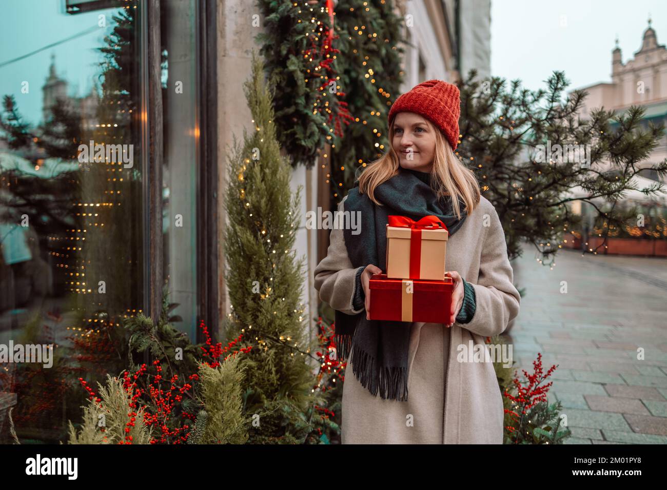 Giovane donna sorridente con la scatola del regalo di natale vicino all'albero di Natale all'aperto al mercato di Natale sulla piazza del municipio a Cracovia, Polonia. amore, inverno Foto Stock