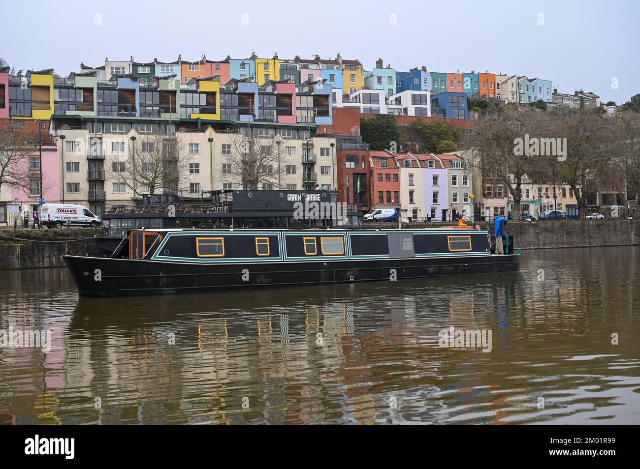 Nuova barca a bordo di un liveaboard che naviga attraverso Bristol attracca una fila di case colorate sullo sfondo. Foto Stock