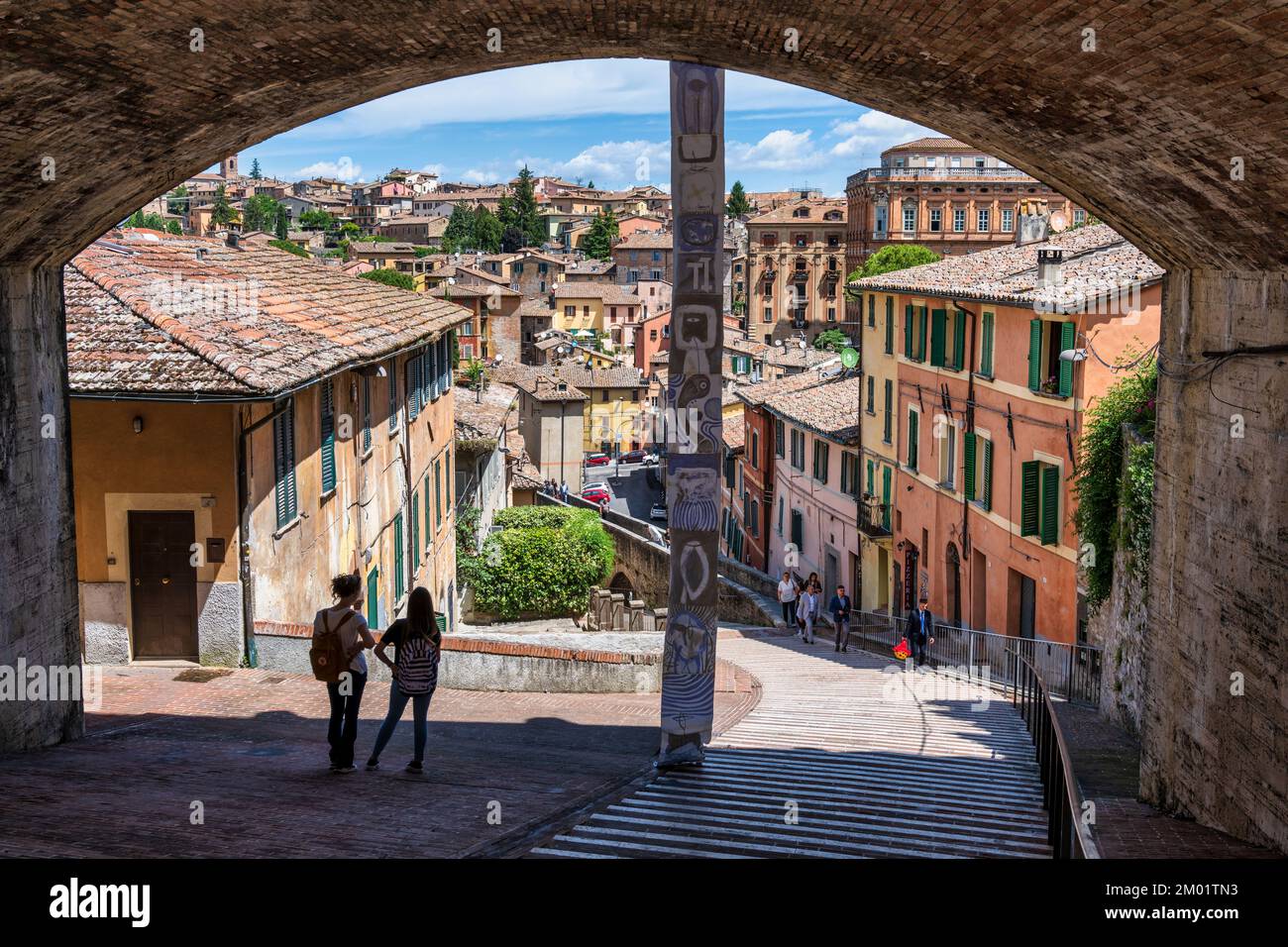 Due giovani si trovano sotto il ponte di Via Cesare Battisti che scende all'acquedotto medievale (Via dell'Acquedotto) di Perugia, Umbria, Italia Foto Stock