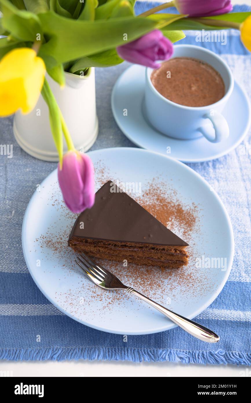 Torta al cioccolato, una tazza di caffè e un mazzo di tulipani Foto Stock