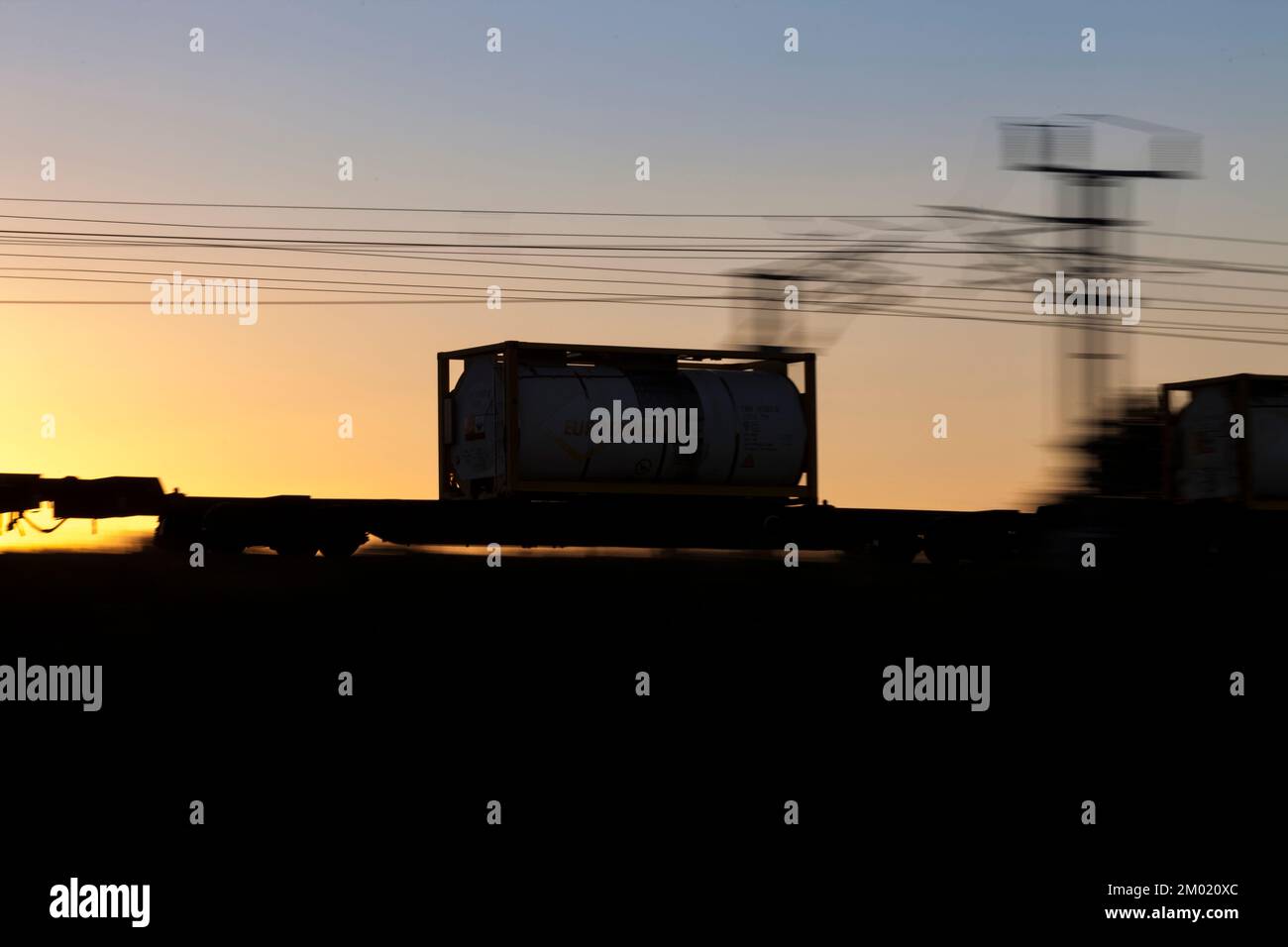 silhouette di un container iso intermodale trasportato su un treno merci ad alta velocità sulla linea principale della costa occidentale. Panoramica con sfocatura del movimento Foto Stock