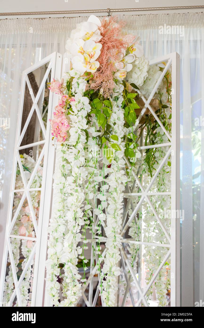 Decorazione della sala banchetti con ghirlande di fiori bianchi e specchi Foto Stock