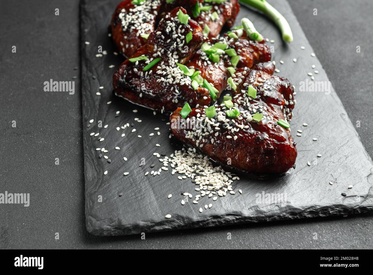 Ali di pollo con sesamo e cipolle verdi. Ricetta asiatica tradizionale. Sfondo scuro. Vista dall'alto. Foto Stock