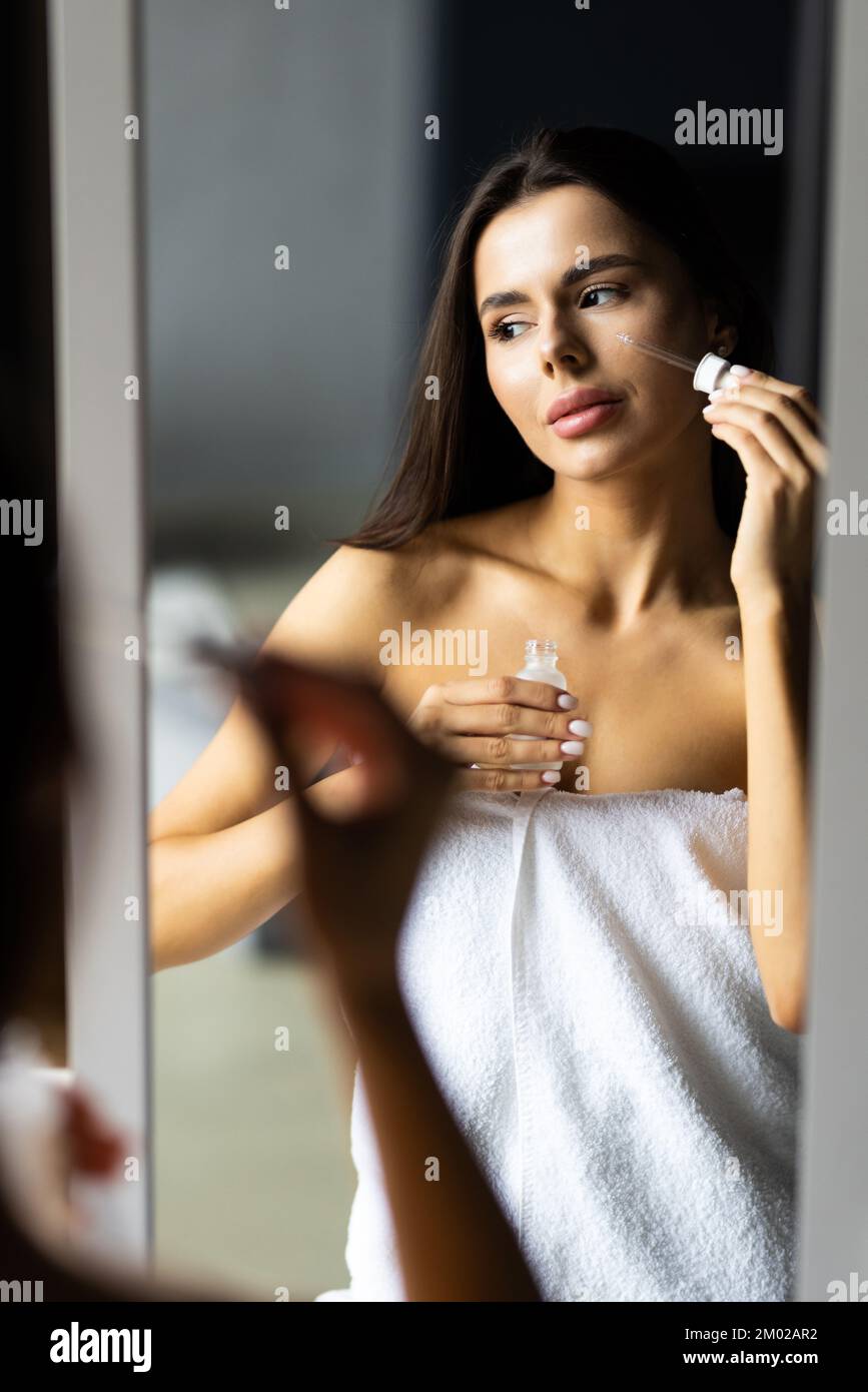Affascinante ragazza mettendo anti-invecchiamento della crema sul suo viso Foto Stock