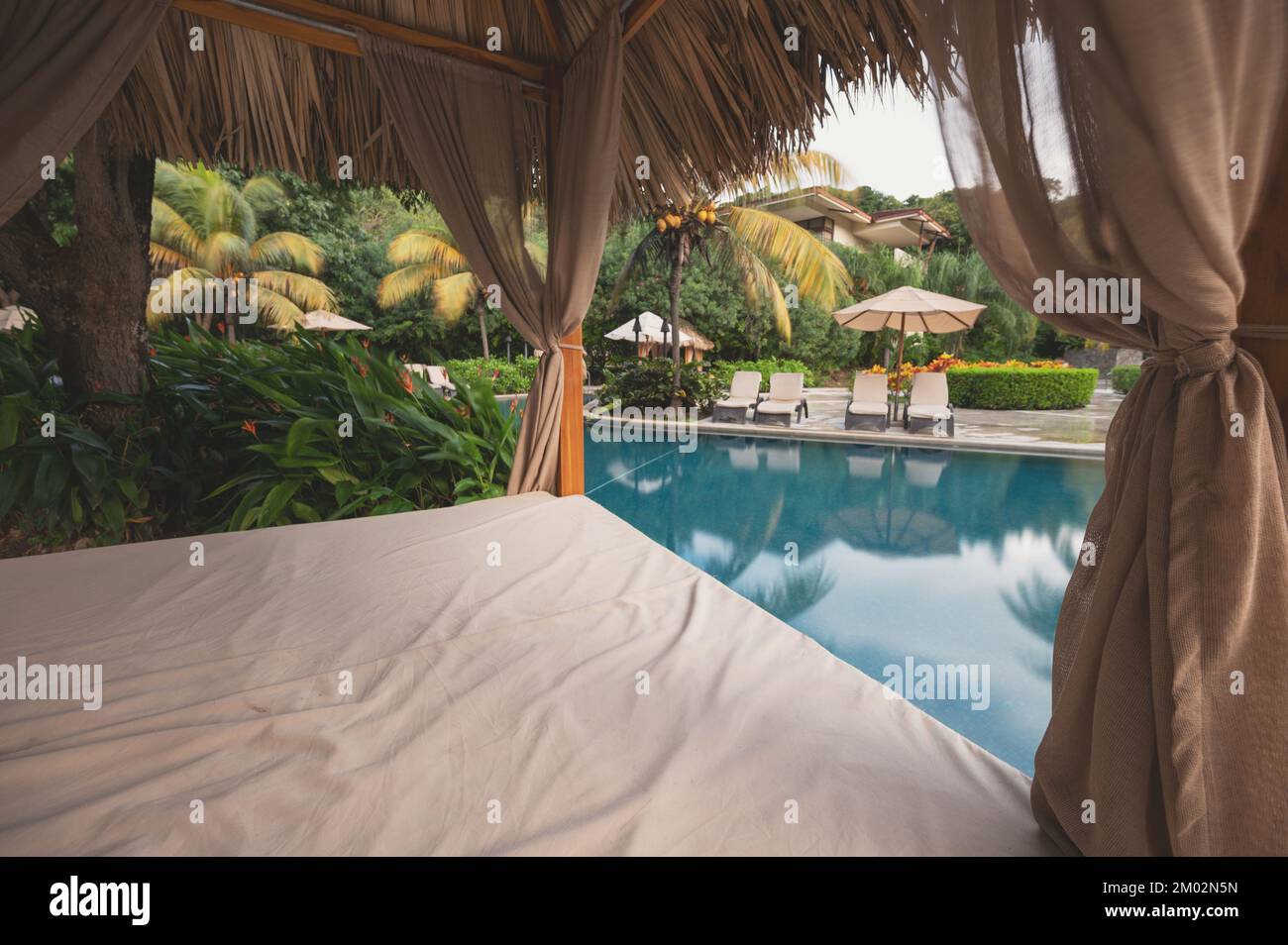 Lettino vuoto accanto alla piscina sullo sfondo del resort Foto Stock