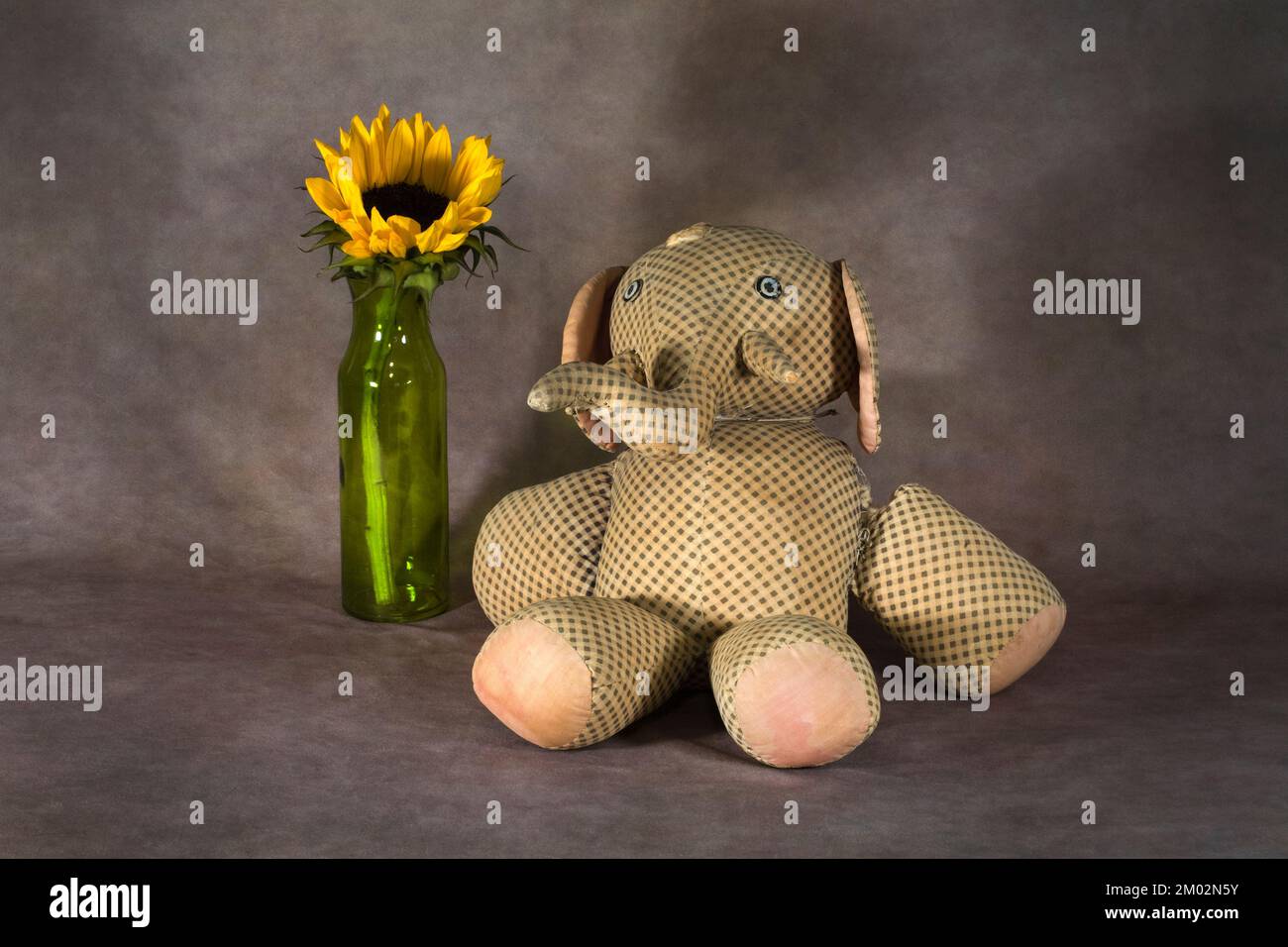 Un bambino di cento anni ripieno elefante giocattolo e una rosa singola in un vaso. Foto Stock