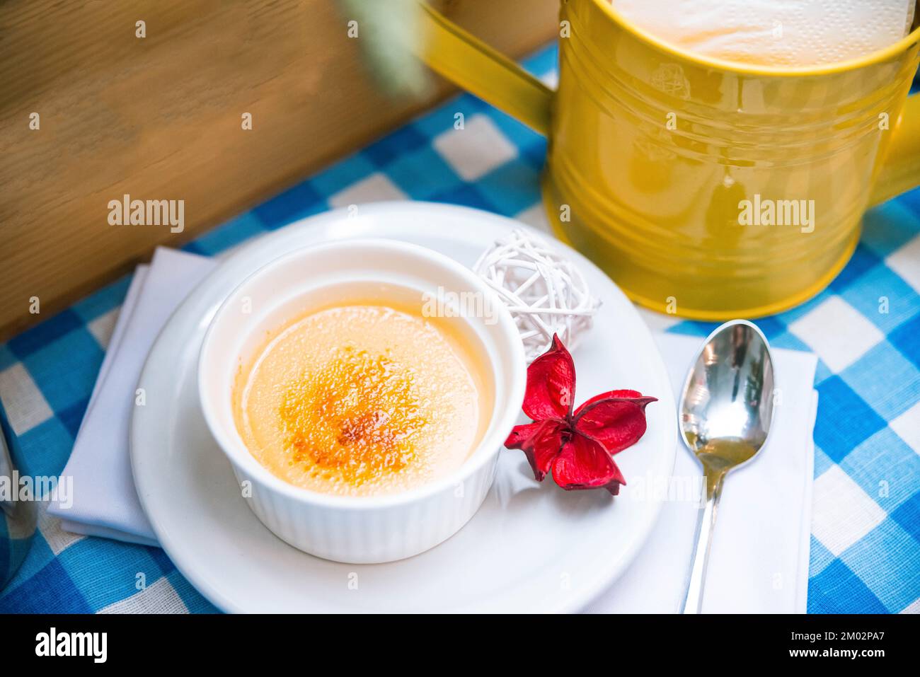 una porzione di delicata crème brulee in ramekin sul tavolo su un tovagliolo a scacchi Foto Stock