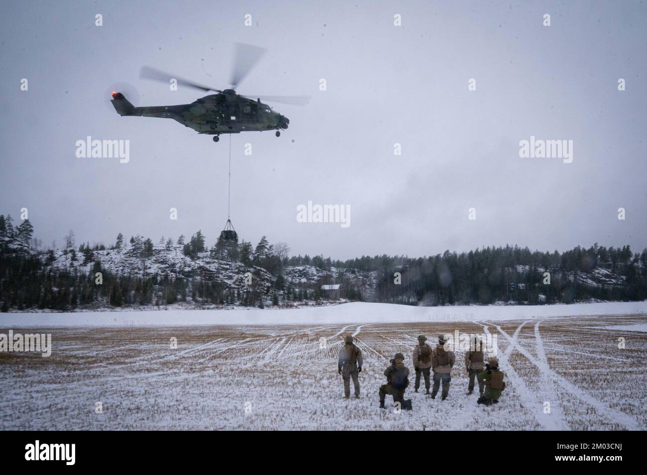 STATI UNITI Marines with Combat Logistics Battalion 6 (CLB-6), Combat Logistics Regiment 2, 2nd Marine Logistics Group, osservare un elicottero ascensore con l'aeromobile finlandese NH90 durante il congelamento Winds 22 a Gumbole, Finlandia 30 novembre 2022. Task Force Red Cloud, con sede centrale da Elements of CLB-6, viene distribuita in Finlandia a sostegno degli esercizi SYD 2022 e Freezing Winds 2022 per migliorare l'interdipendenza tra Stati Uniti e Finlandia nel settore marittimo; consolidare la manovra marittima bilaterale all'interno dell'ambiente litoraneo finlandese; e promuovere solide relazioni tra gli Stati Uniti Corpo marino e forza di difesa finlandese Foto Stock