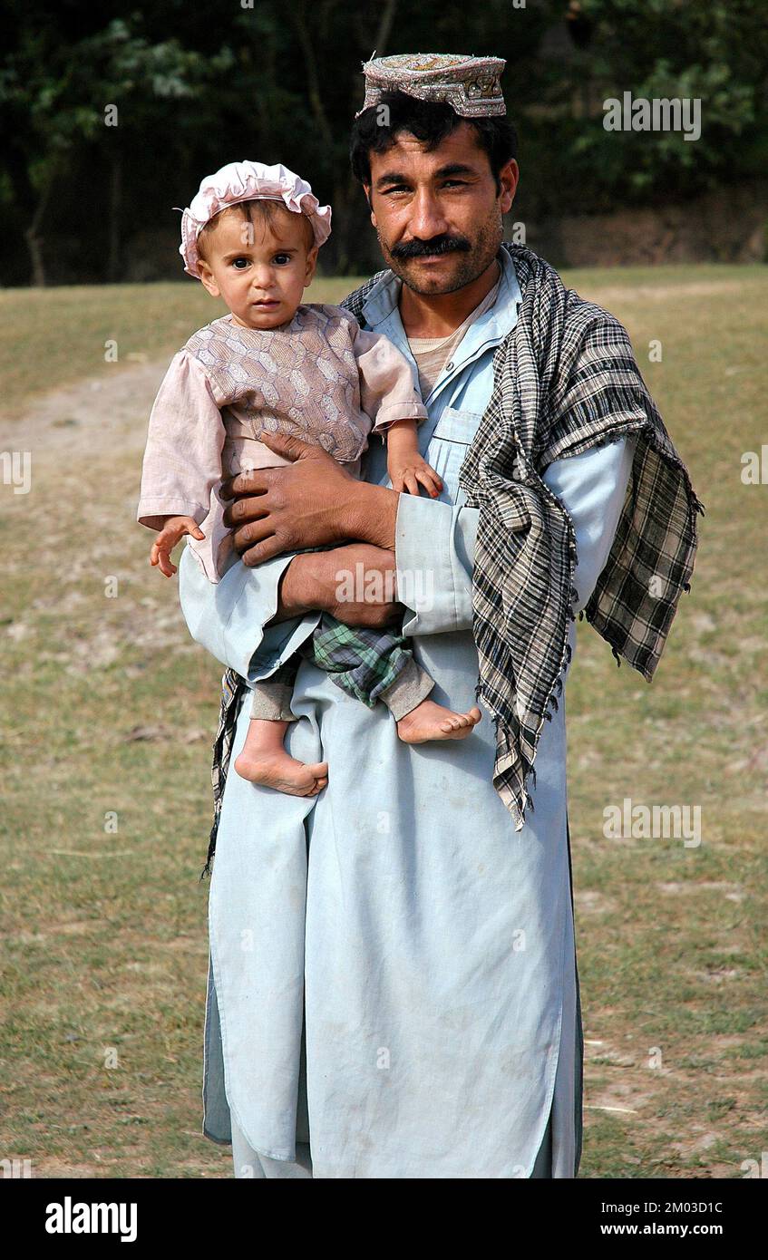 Un piccolo villaggio tra Chaghcharan e il Minareto di Jam, Provincia di Ghor / Afghanistan: Un afghano con un grande baffi in possesso di un bambino. Foto Stock