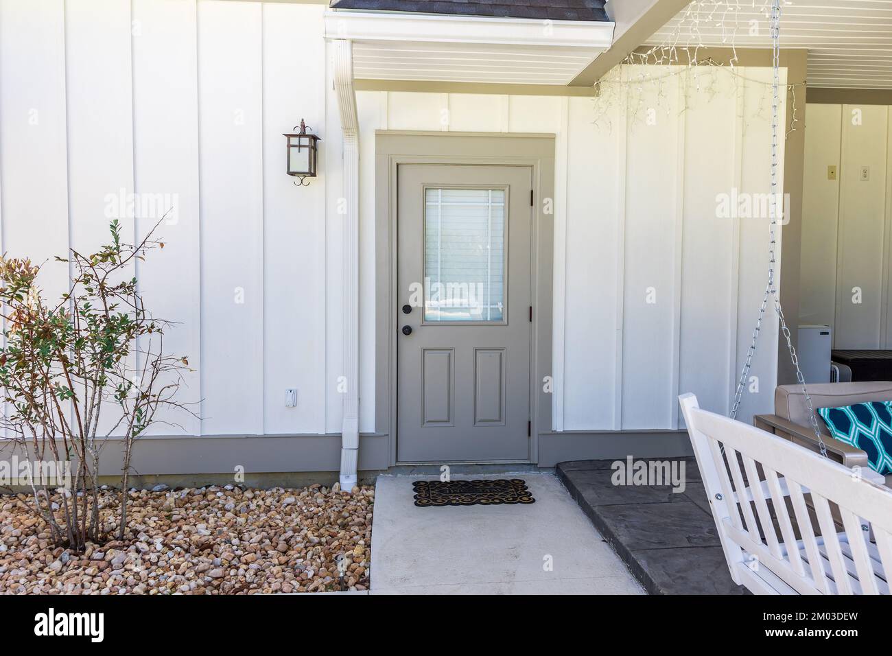 Una porta posteriore lato posteriore taupe di una nuova costruzione color crema casa con pannelli duri che si siede vicino all'entrata del patio Foto Stock