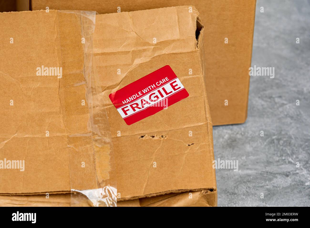 Scatola di cartone danneggiata con etichetta fragile. Concetto di assicurazione pacco, consegna posta e termine di spedizione Foto Stock