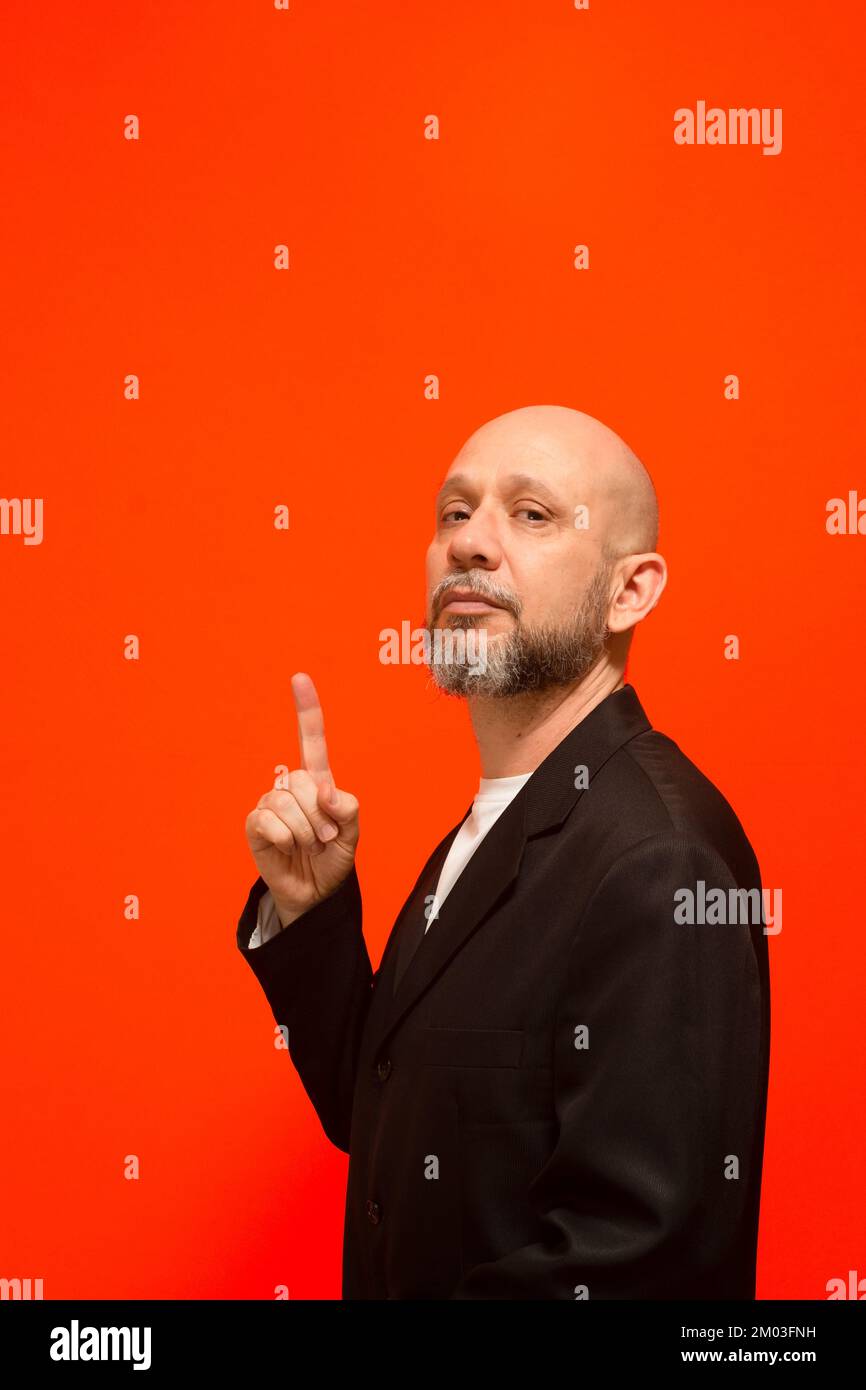 Uomo d'affari, maturo, elegante, puntando il dito verso l'alto. Isolato su sfondo arancione. Foto Stock