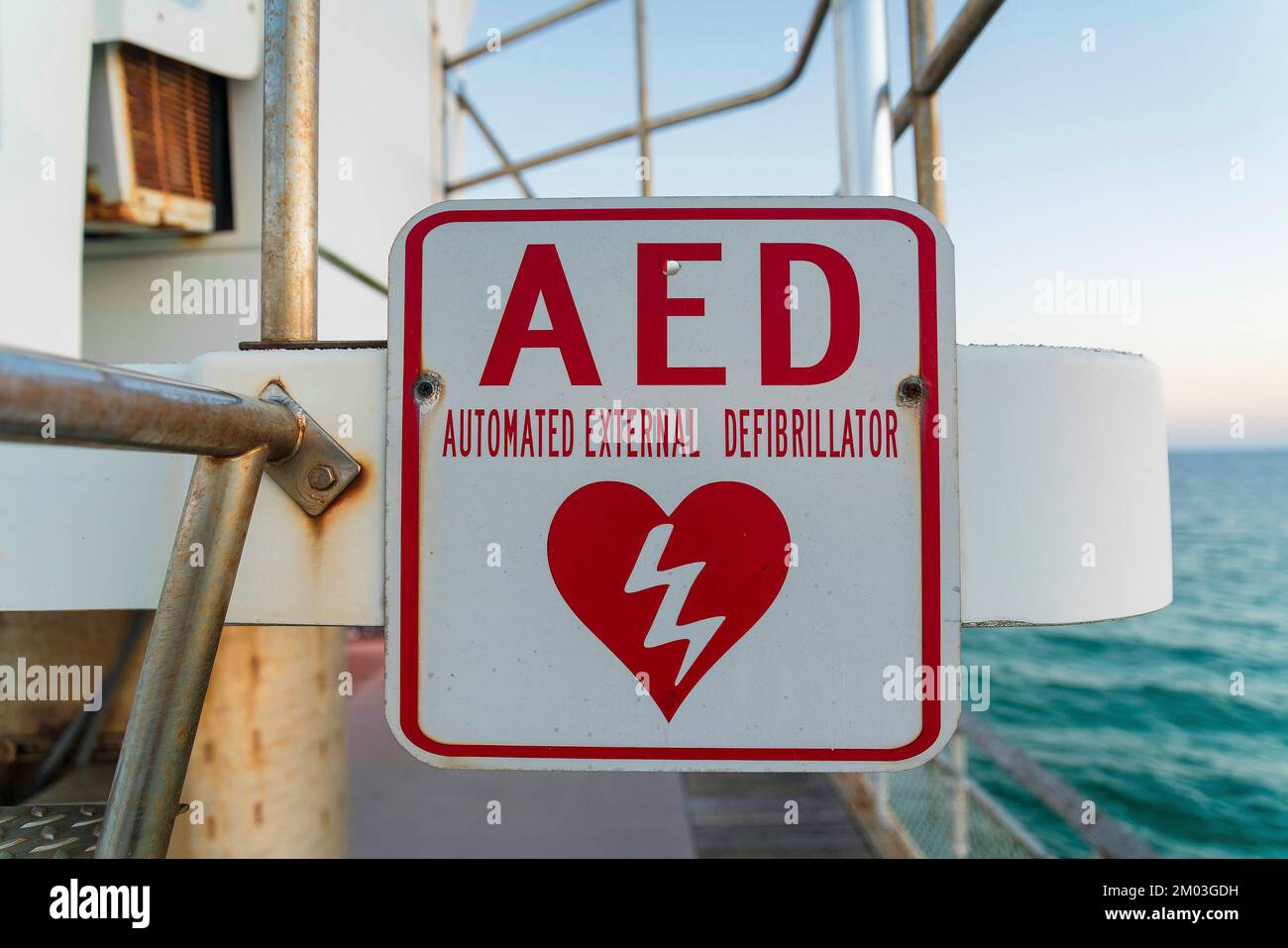 Destin, Florida - segnaletica per defibrillatore semiautomatico esterno su un molo. Primo piano di un cartello su una ringhiera d'acciaio e vista sull'oceano sul retro Foto Stock