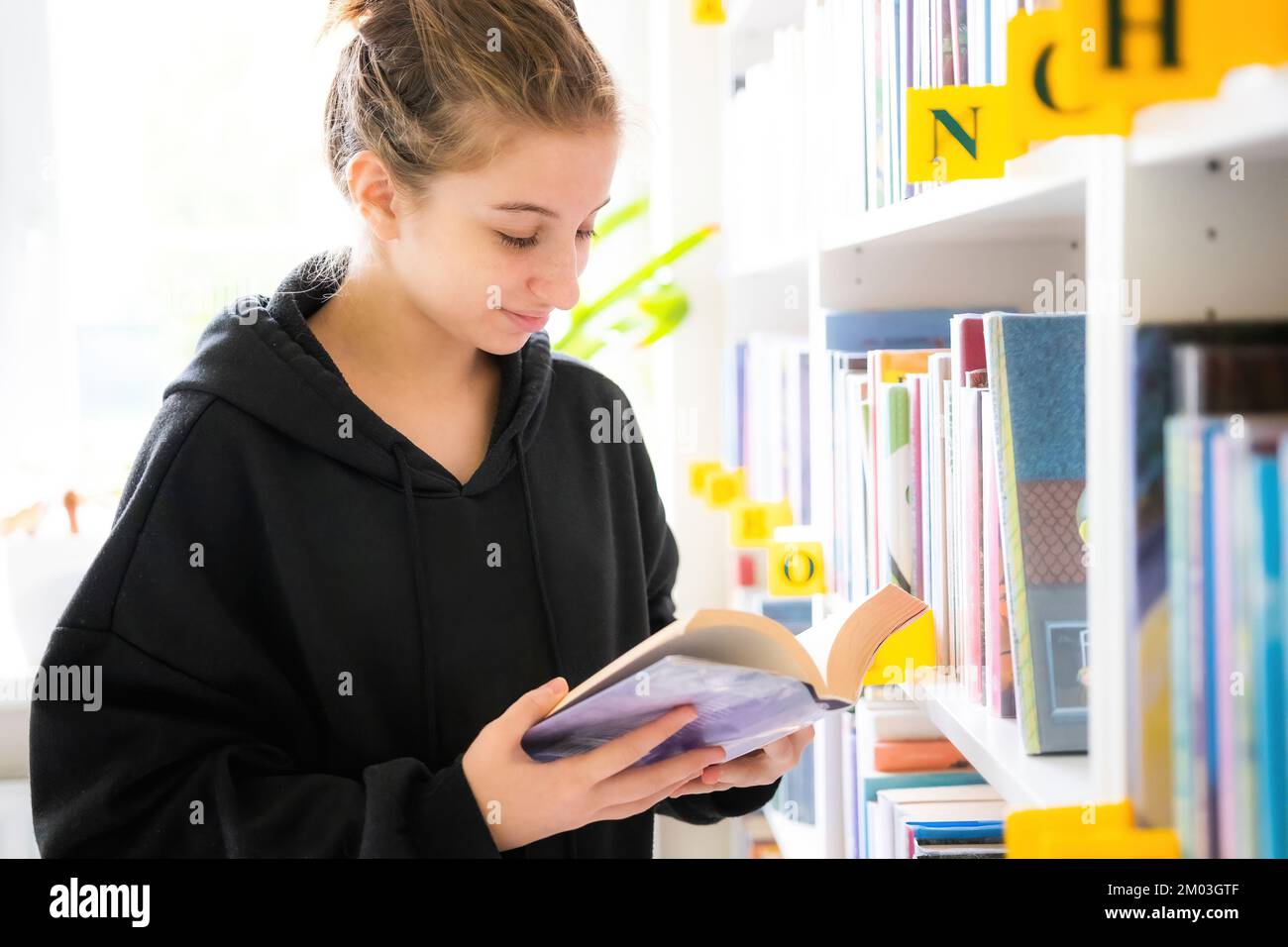 ragazza adolescente cerca il libro giusto nella biblioteca della scuola Foto Stock