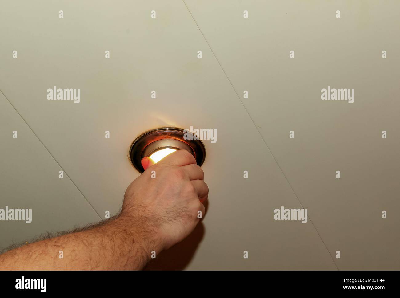 Installando un faretto, la mano inserisce la lampada nel soffitto. Sostituzione di una lampadina a incandescenza bruciata. Foto Stock