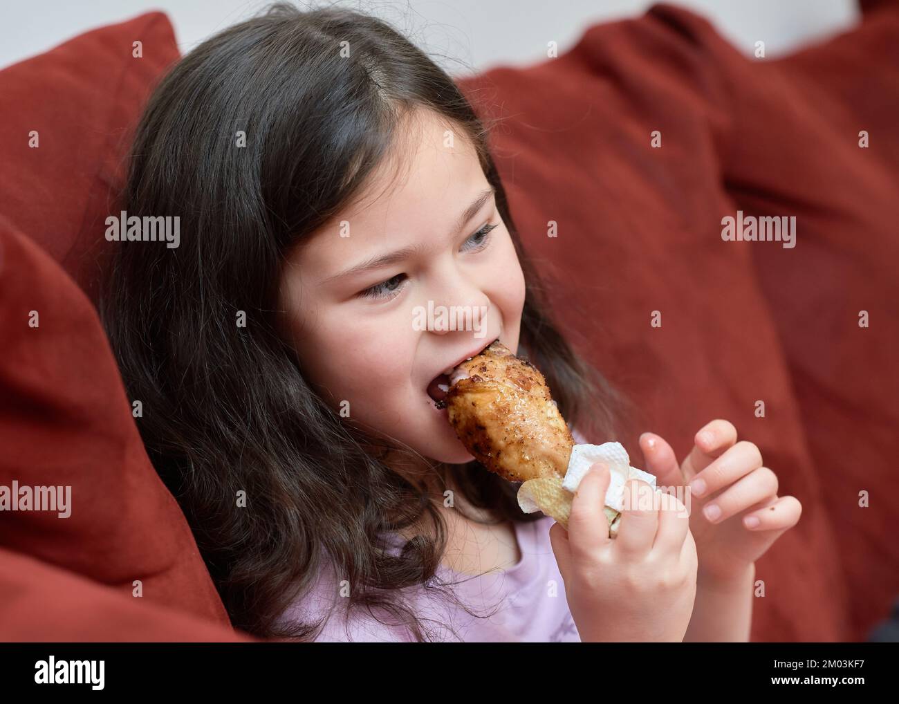 La giovane ragazza espressiva mangia pollo e verdure per cena sul divano  mentre guarda la TV Foto stock - Alamy