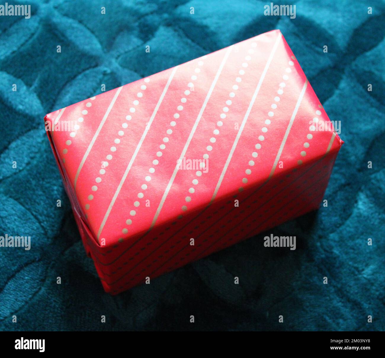 Una piccola confezione regalo confezionata in carta rossa e oro Foto Stock