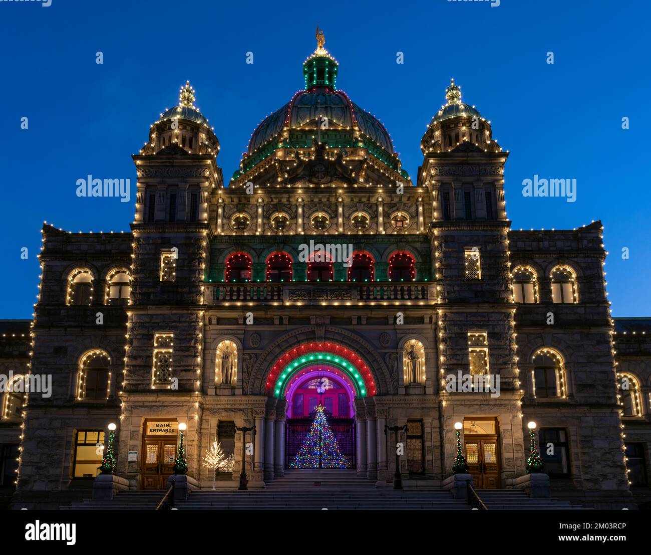 Gli edifici del Parlamento della Columbia Britannica a Victoria, visti al crepuscolo con le luci di festa e un albero di Natale. Foto Stock