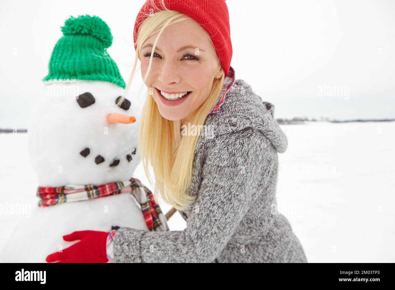 Natale, vacanza e donna con pupazzo di neve in inverno ritratto vacanza, felice edificio con neve e celebrazione. Spirito di festa con tradizione natalizia Foto Stock