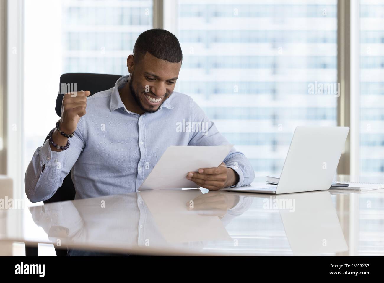 Felice eccitato giovane uomo d'affari nero ottenendo buona lettera di notizie Foto Stock