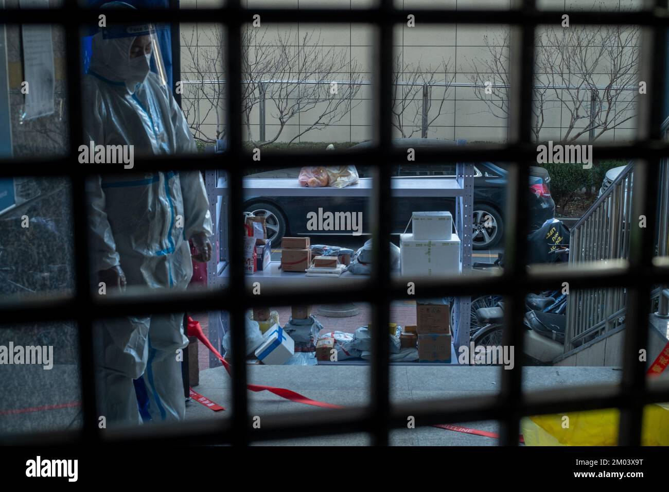 Un operaio di comunità in tuta protettiva guardie all'ingresso di un appartamento residenziale chiuso a Pechino, Cina. Foto Stock