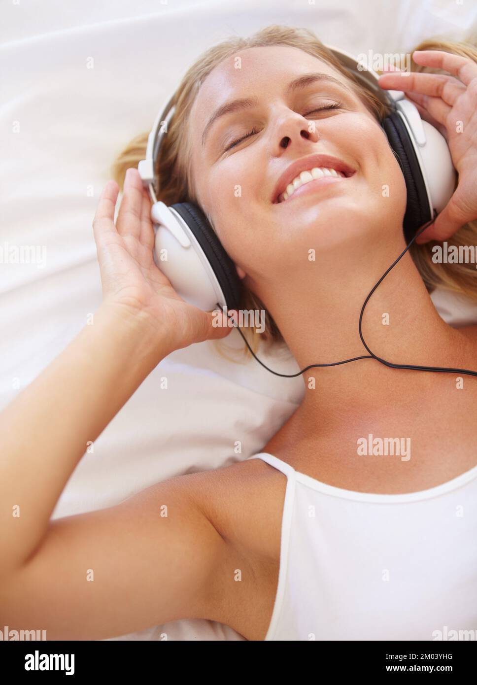 Rilassarsi con la sua musica. Una giovane donna attraente che ascolta musica mentre sdraiata sul suo letto. Foto Stock