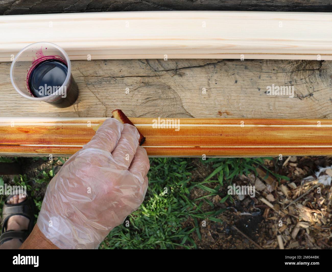 colorare i filetti di legno con una spugna di schiuma e una soluzione di manganese di borgogna in un'officina di falegname di villaggio Foto Stock