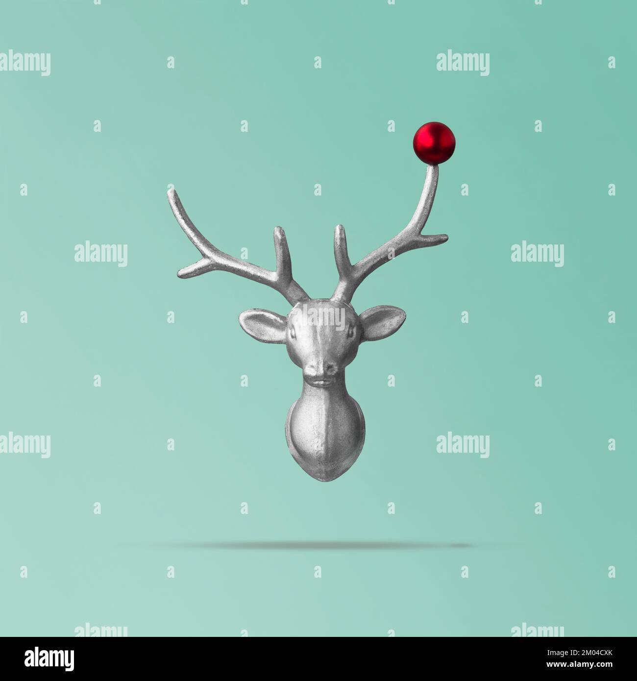 Concetto di renna di Natale su sfondo teal fatto di testa di renna e rosso bauble. Idea di vacanza invernale minima, concetto di nuovo anno Foto Stock