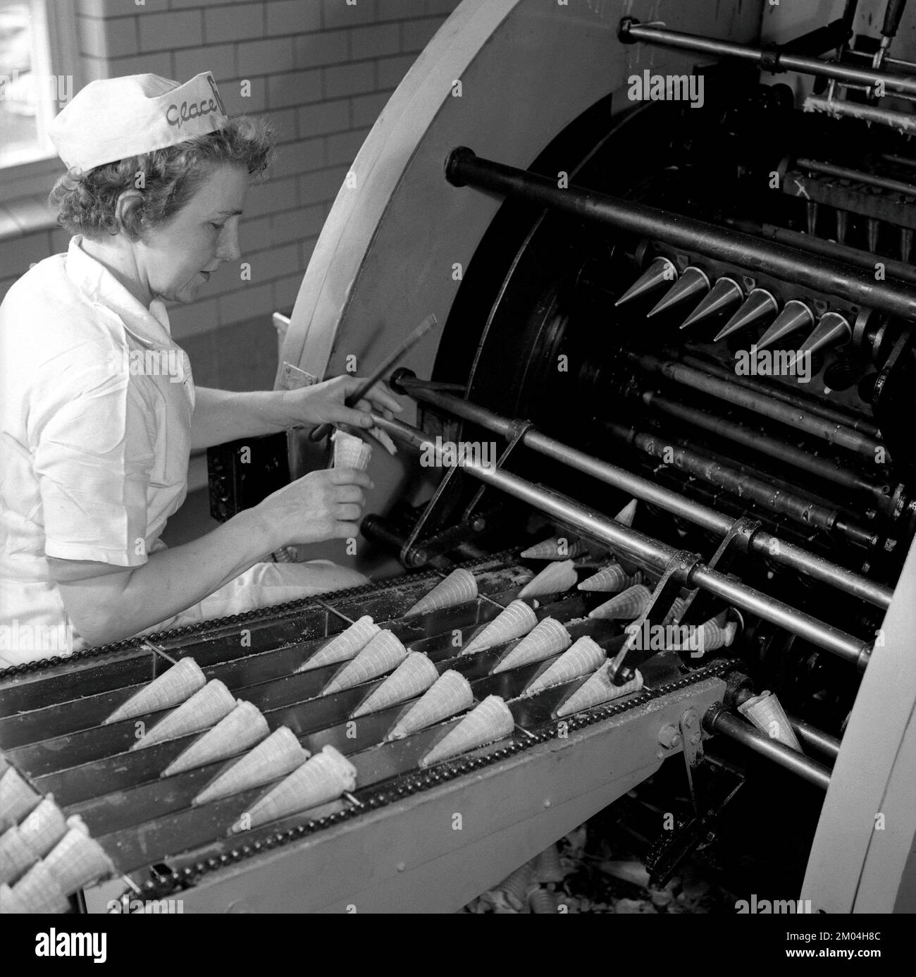 Gelato nel 1960s. All'interno di una fabbrica di gelato dove una donna che ho visto accanto a una macchina che dispone i waffle prima che siano riempiti con gelato. Svezia 1965 rif CS100-6 Foto Stock