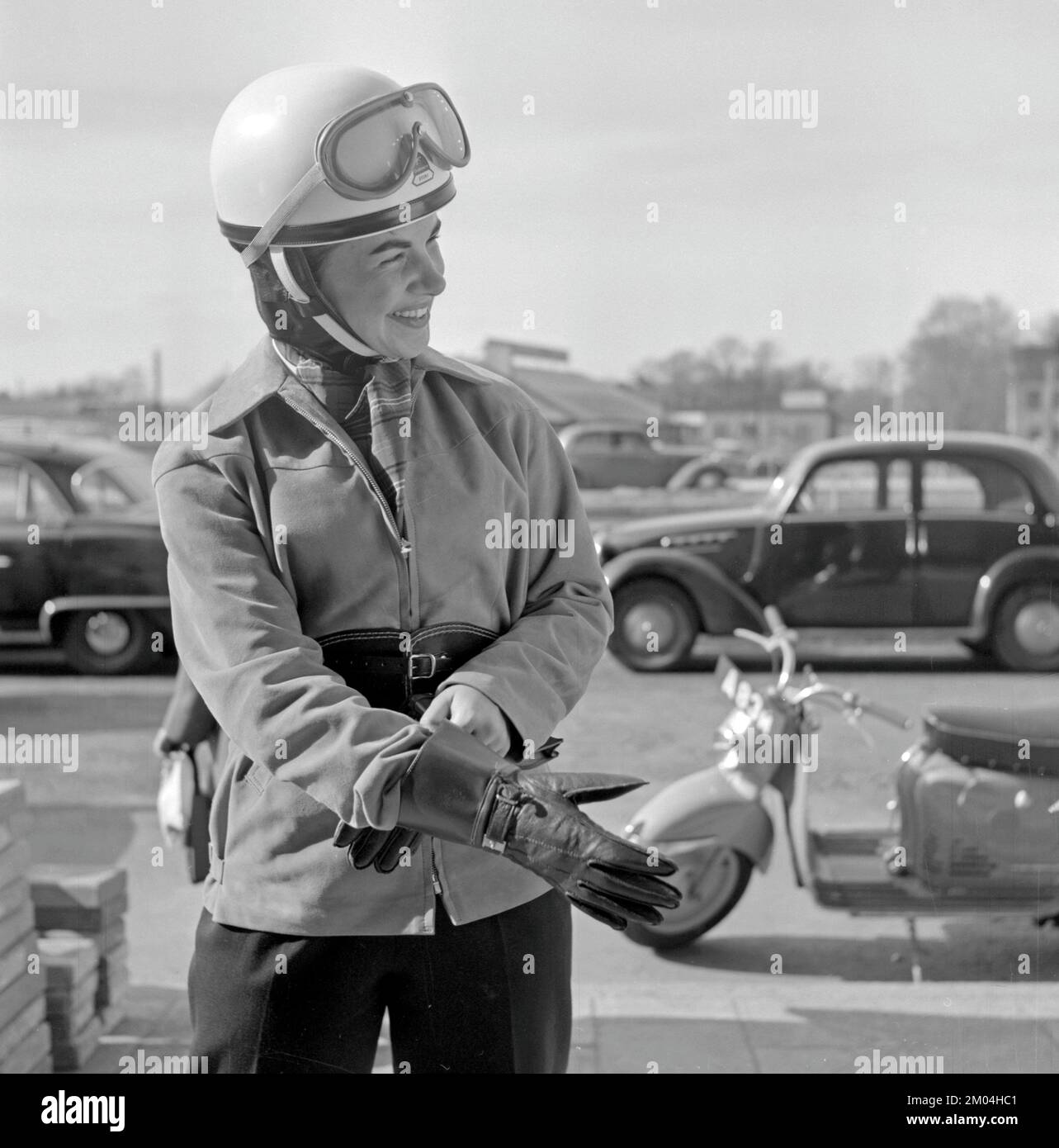 Negli anni '1950s. Una giovane donna vista su uno scooter Puch di origine tedesca. L'autista femminile indossa i tipici abiti e accessori per motociclette del decennio, casco, giacca, cintura renale e guanti. Svezia 1955 Foto Stock