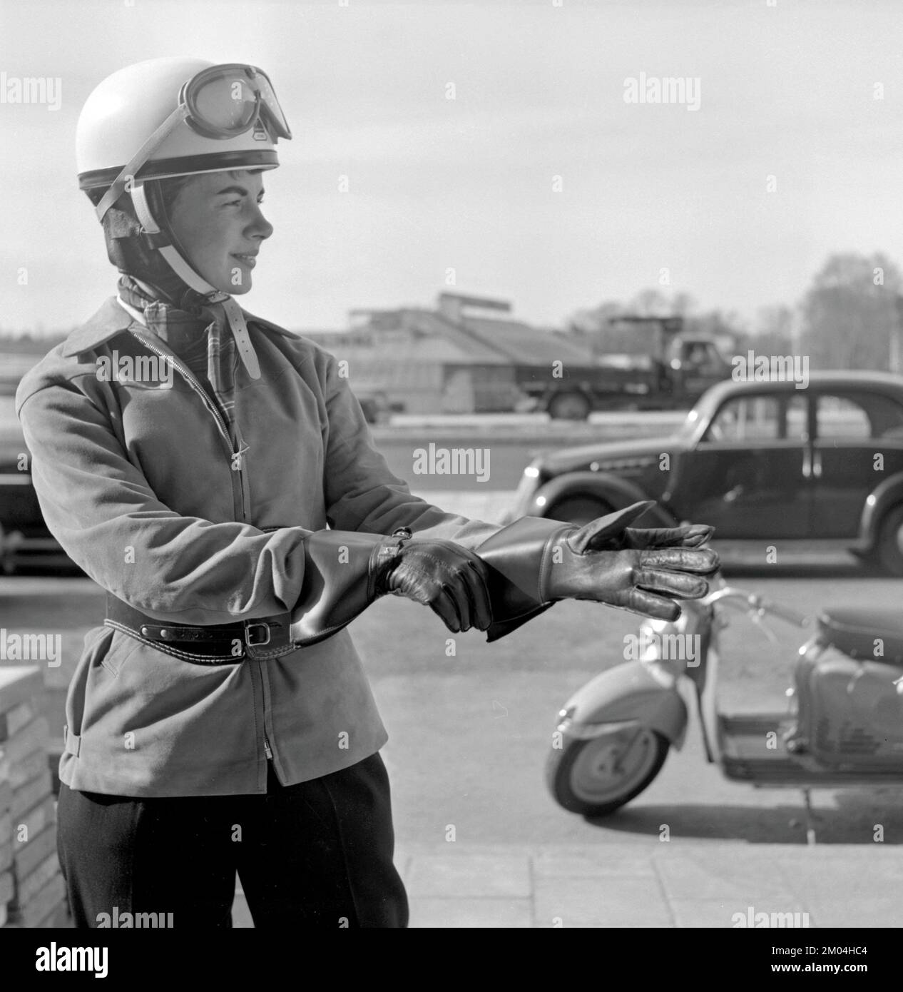 Negli anni '1950s. Una giovane donna vista su uno scooter Puch di origine tedesca. L'autista femminile indossa i tipici abiti e accessori per motociclette del decennio, casco, giacca, cintura renale e guanti. Svezia 1955 Foto Stock