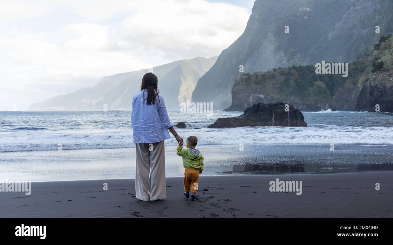 Madre e bambino piccolo che tiene le mani camminare sul lato del mare Foto Stock