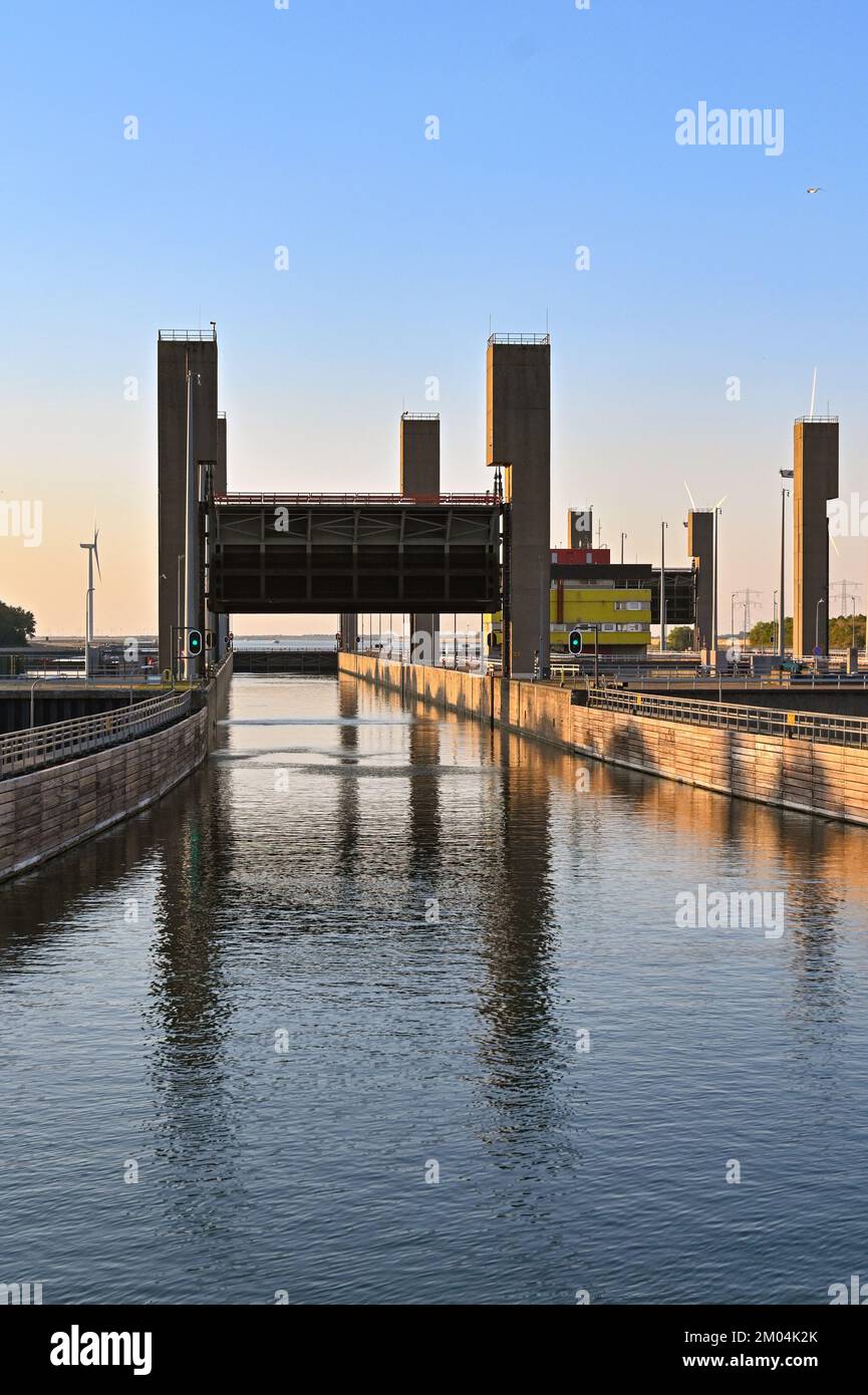 Rilland, Paesi Bassi - 2022 agosto: Ingresso a una grande serratura del canale al crepuscolo con il cancello della serratura sollevato per consentire alle navi di entrare Foto Stock Rilland, Paesi Bassi - 2022 agosto: Ingresso a una grande serratura del canale al crepuscolo con il cancello della serratura sollevato per consentire alle navi di entrare Foto Stock