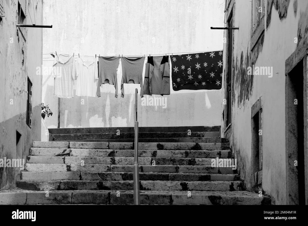 Tipica strada stretta con scale in pietra e clothesline in Alcacer do SAL, Portogallo Foto Stock