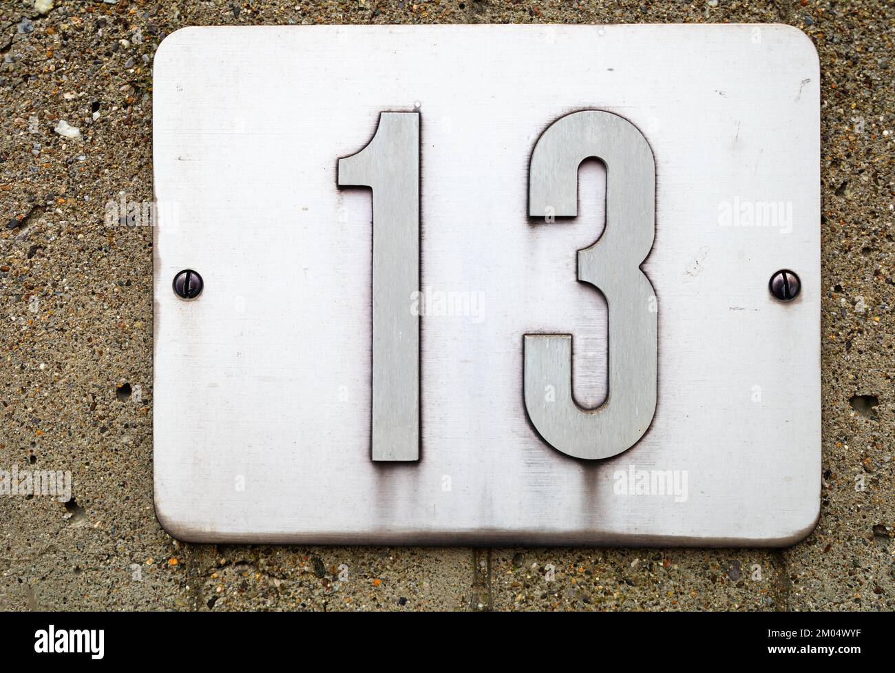Numero 13 su una piastrella metallica, fissata a parete Foto Stock