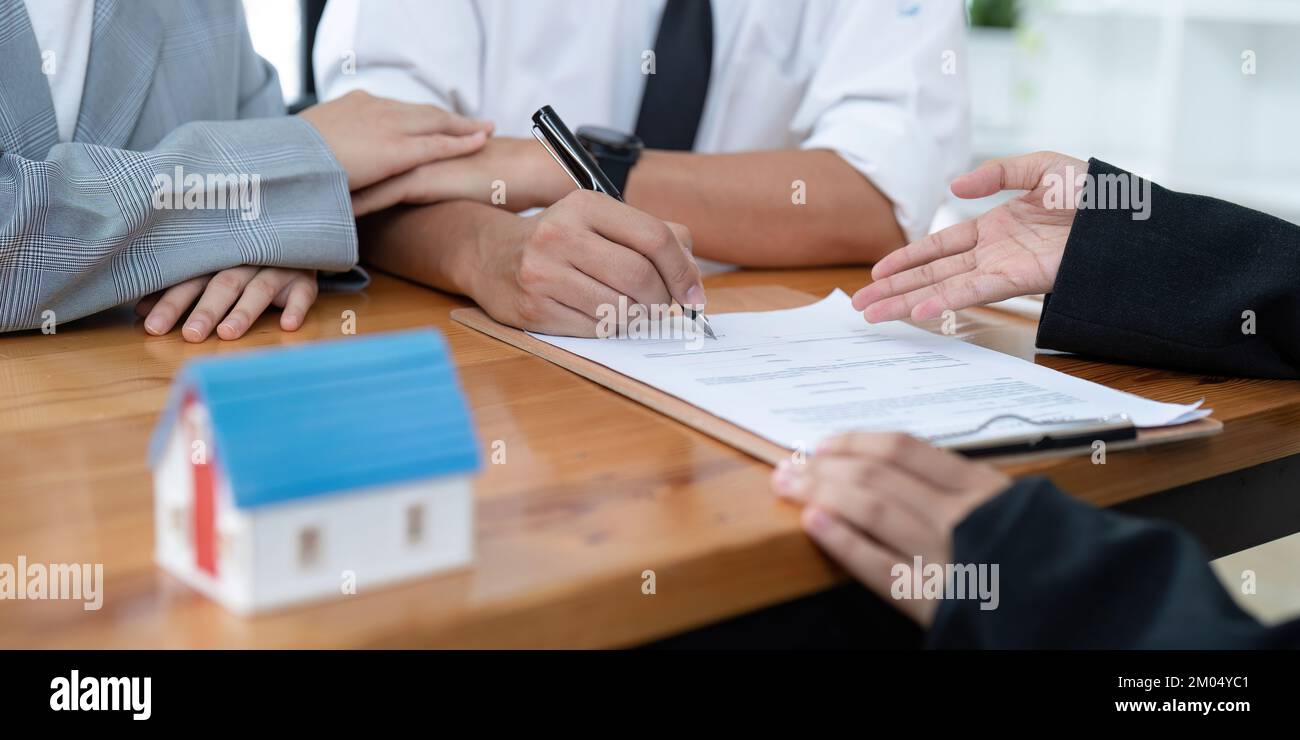 Giovane coppia firmando un contratto con un agente immobiliare. Foto Stock