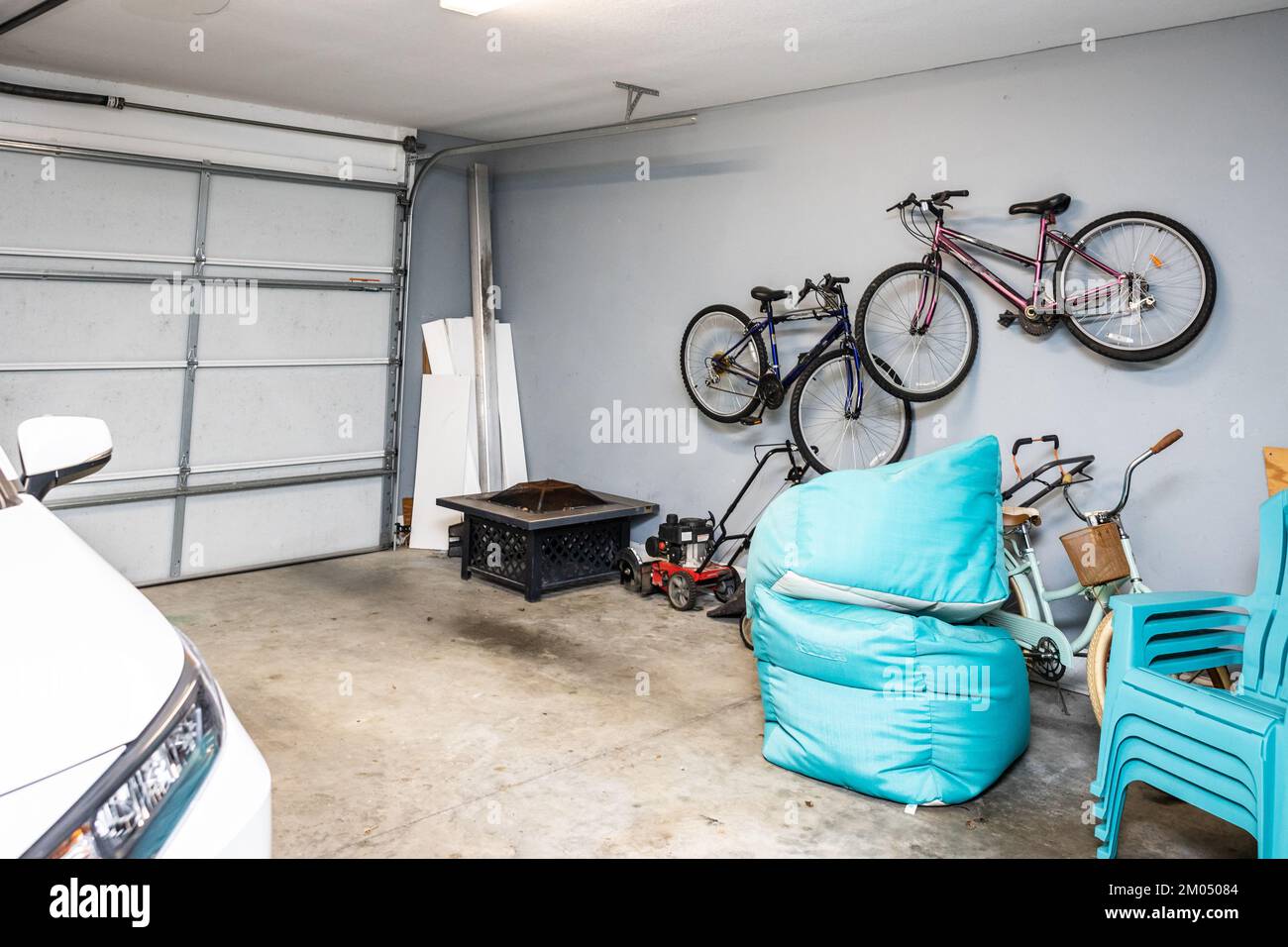Un garage a due posti che è per lo più vuoto con un'auto e biciclette organizzate e appese al muro Foto Stock