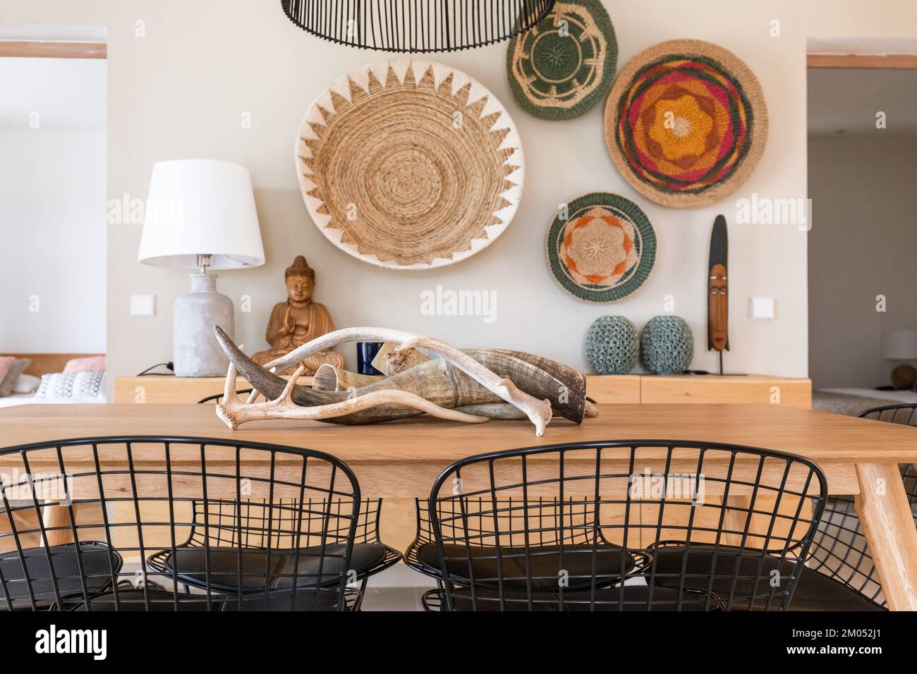 Le pareti della villa mediterranea sono decorate con una statua in legno di buddha e una maschera africana, piantatrici rotonde in vimini tipiche della regione Foto Stock