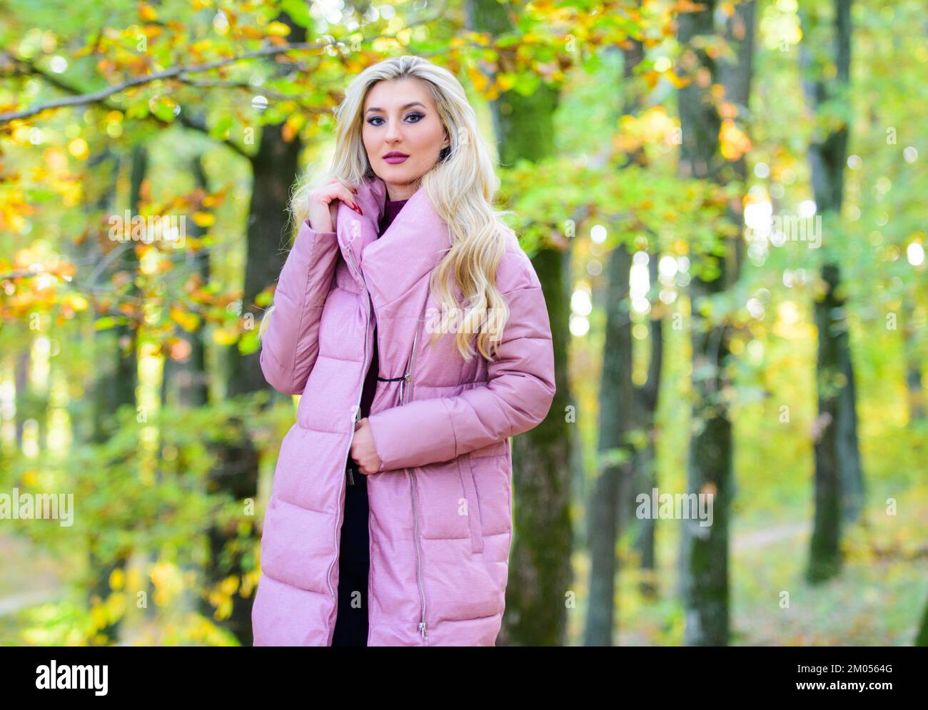 Giacche che tutti dovrebbero avere. Ragazza alla moda bionda passeggiata nel parco. Migliori cappotti puffer da comprare. Come fare a rock giacca puffer come stella. Moda puffer Foto Stock