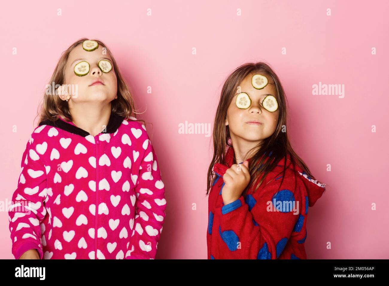 Bambini con facce gravi, cetrioli sugli occhi e capelli sciolti Foto Stock